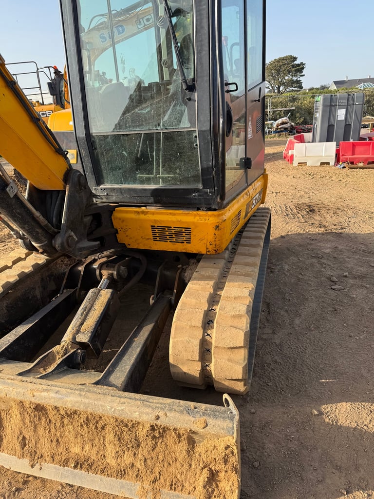 Yellow and black mini excavator parked on sandy ground at a construction equipment lot